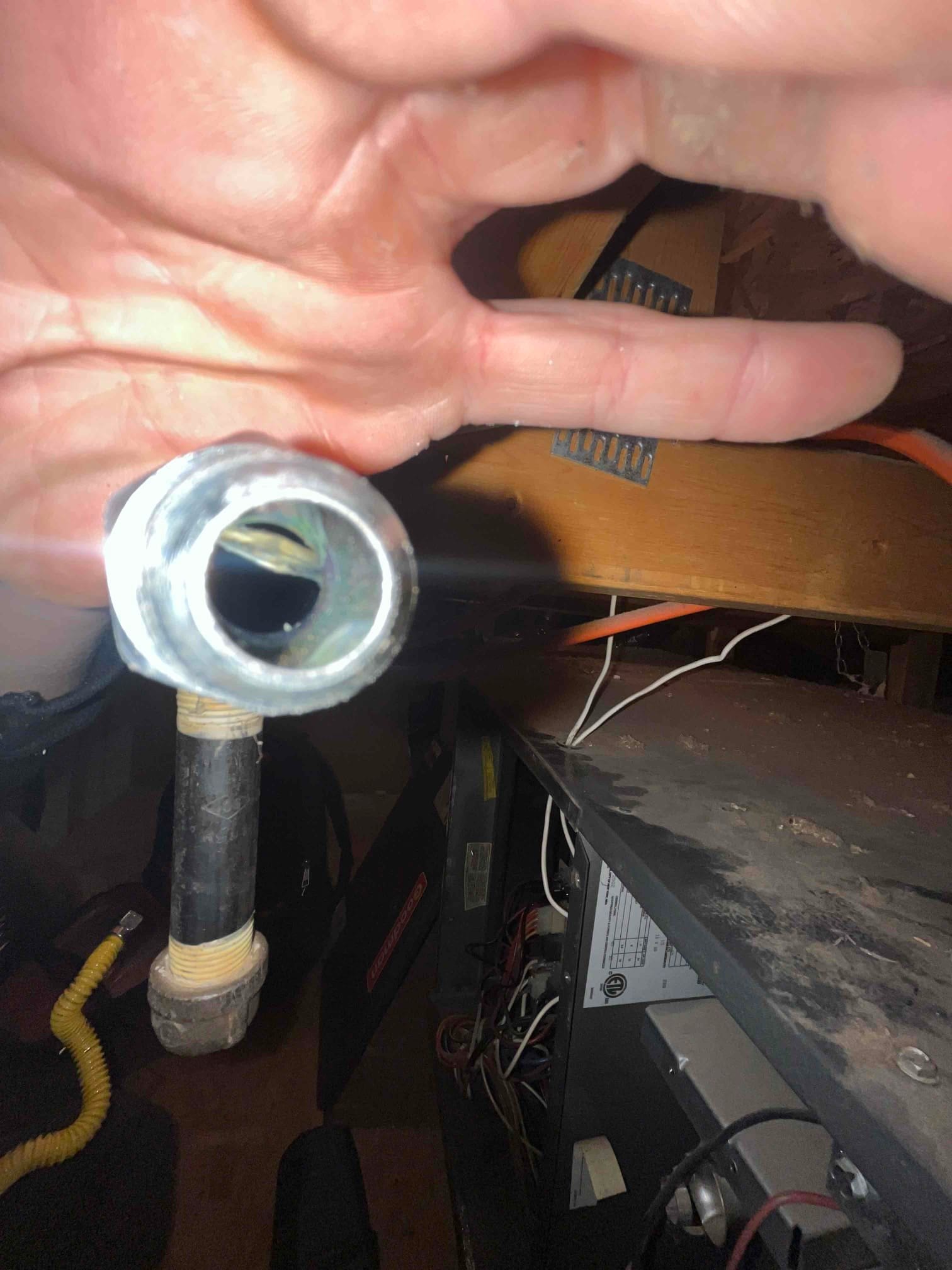 Open furnace cabinet shows internal wiring and control compartment, with nearby black iron gas pipe wrapped with thread sealant and yellow connector.