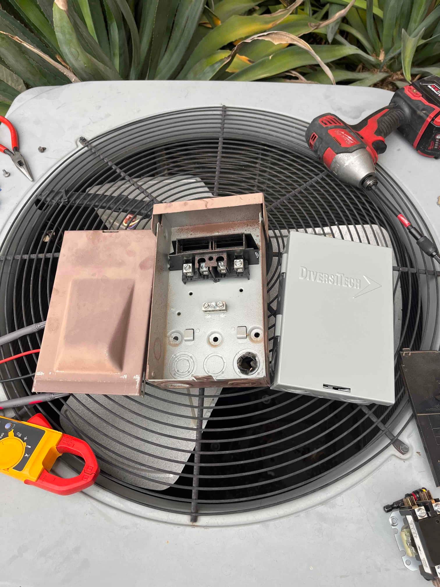 Outdoor condenser top shows an open electrical disconnect enclosure with cover and pullout removed, tools and a contactor nearby.