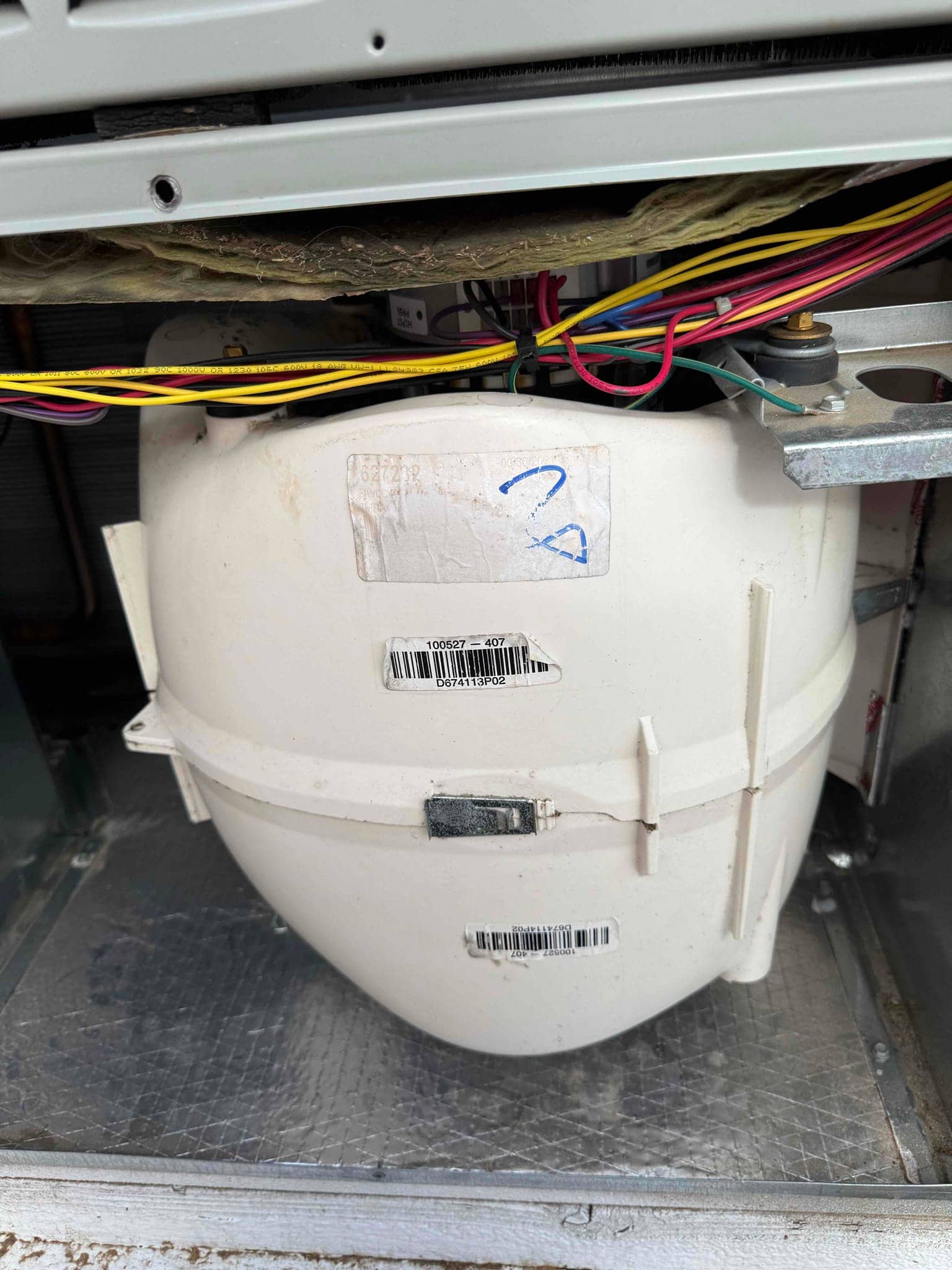 Plastic blower housing inside the air handler cabinet with wiring above and a visible crack near the latch.