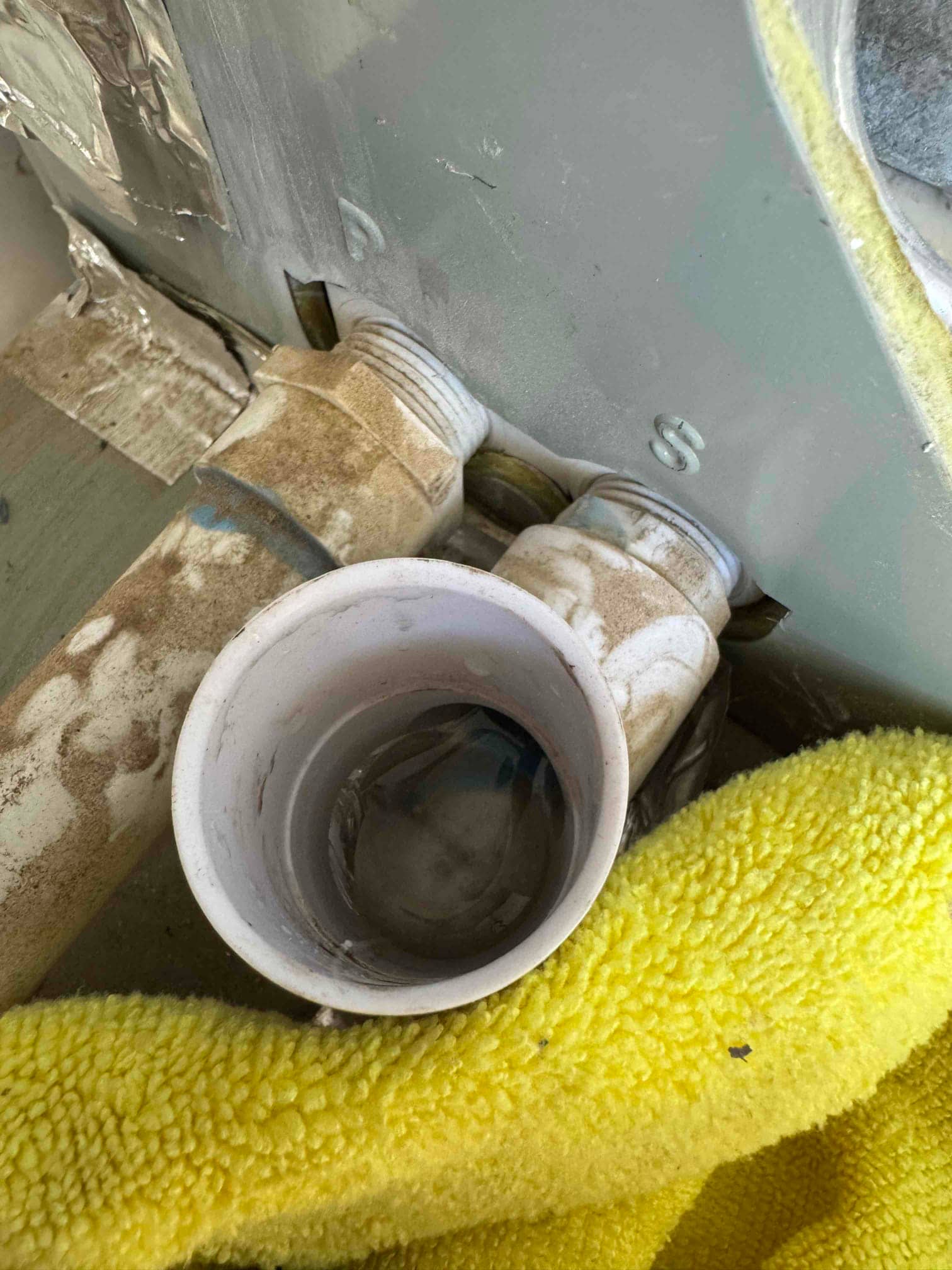PVC condensate drain cleanout at air handler, cap removed showing water in the tee fitting.