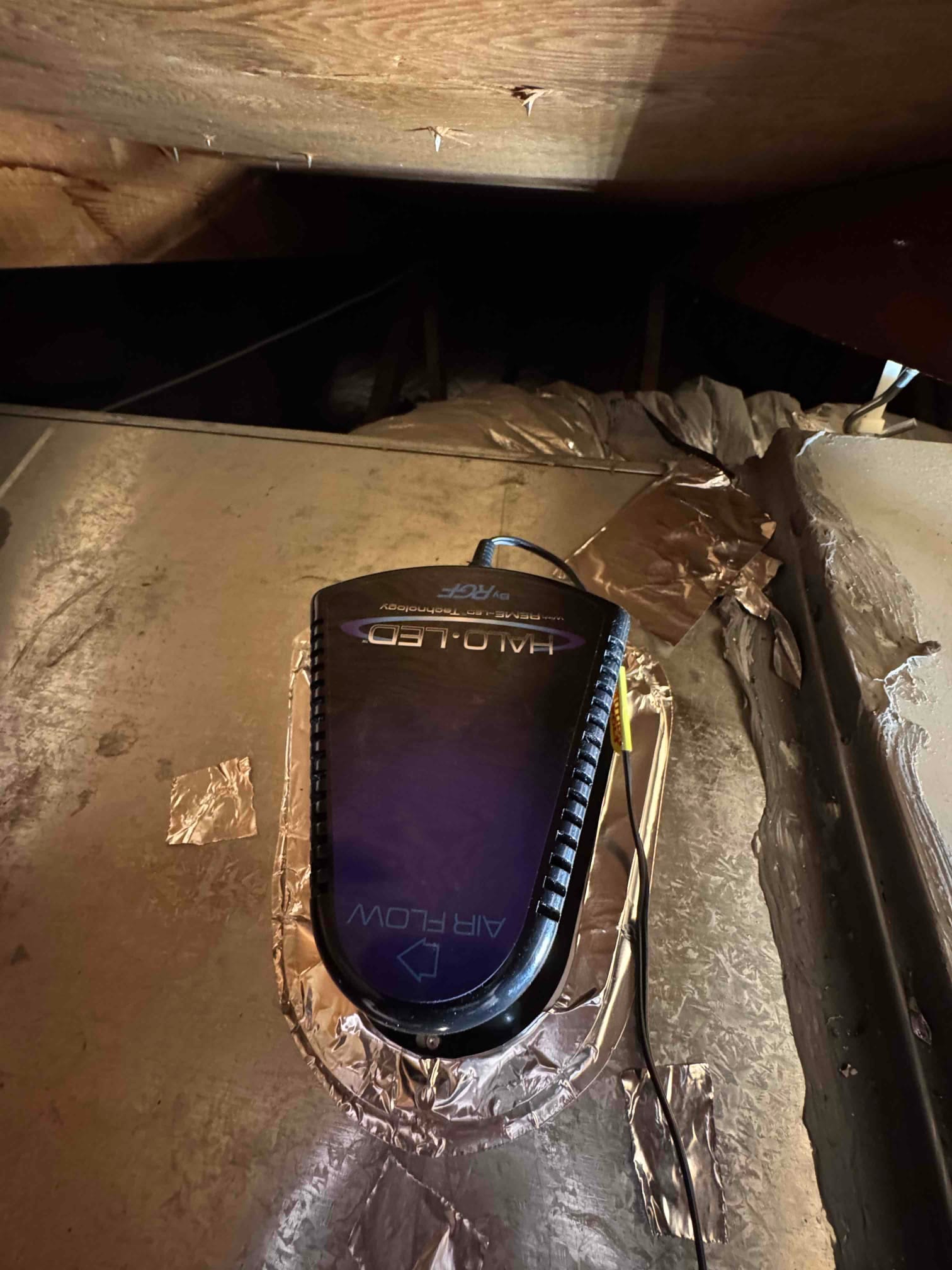 UV air treatment device mounted on supply plenum with foil tape sealing and wiring visible.