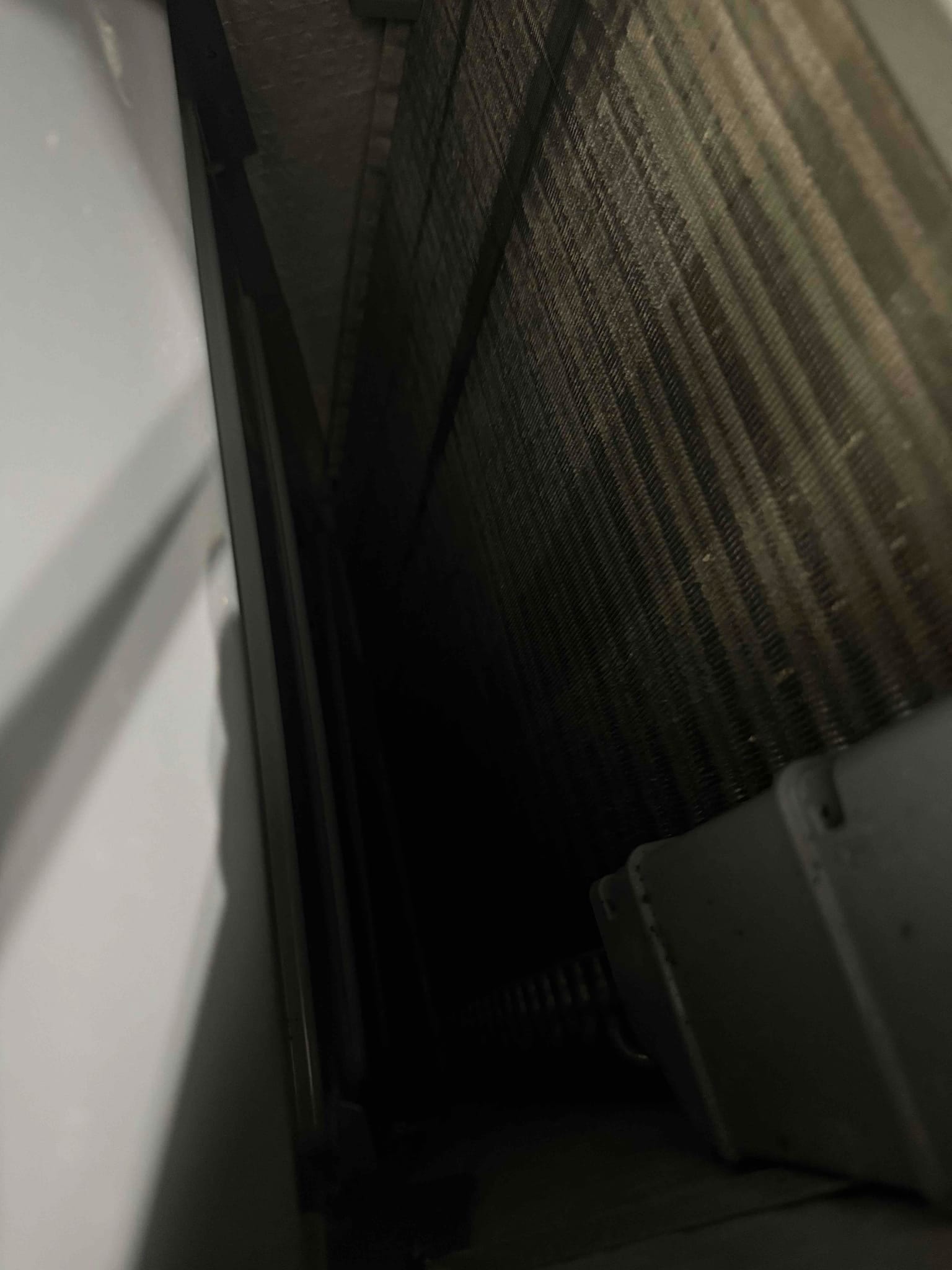 View inside indoor unit showing A-frame evaporator coil fins and drain pan along the base.