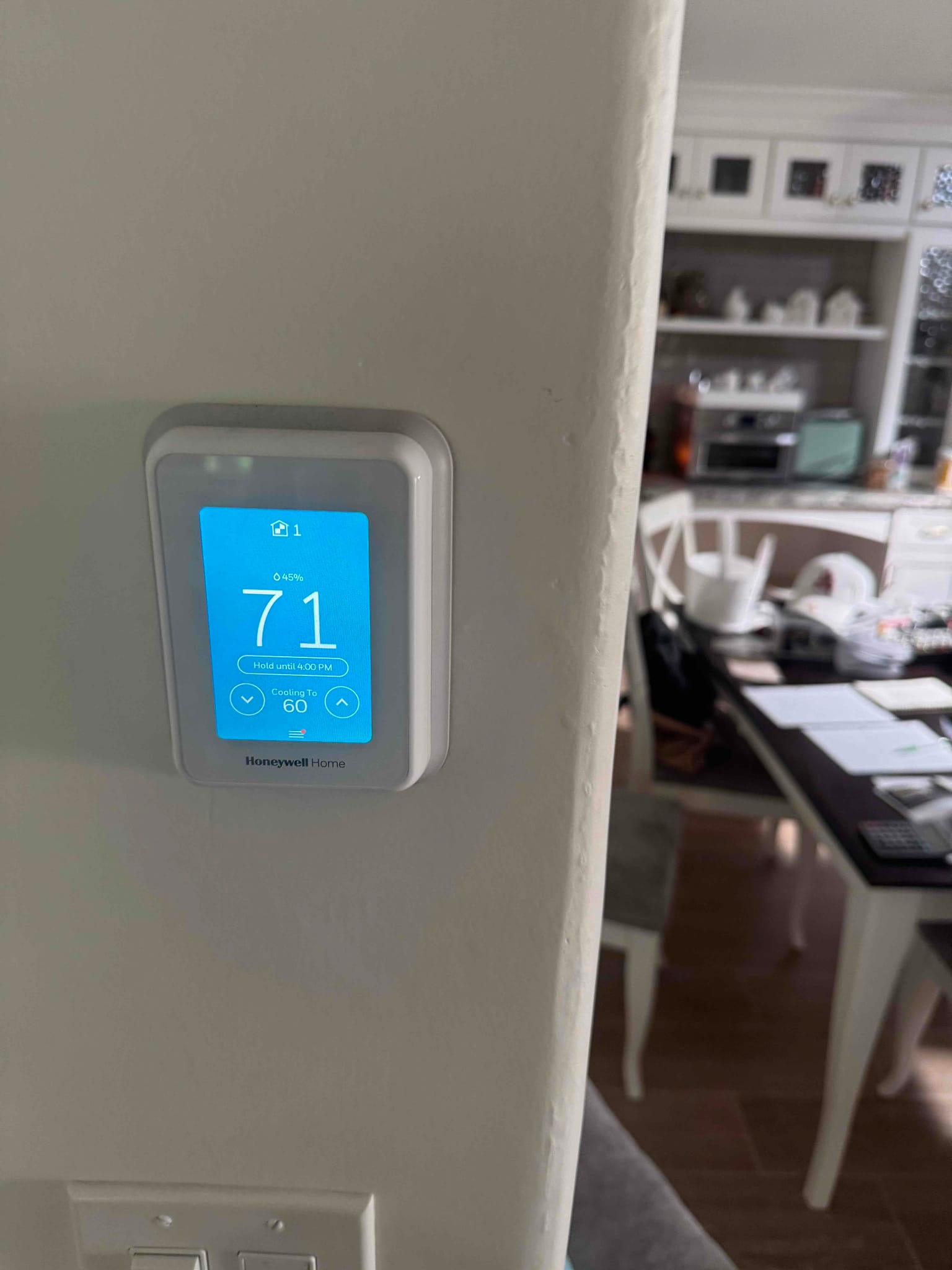 Wall-mounted digital thermostat displays 71°F and setpoint for cooling to 60°F with hold active.