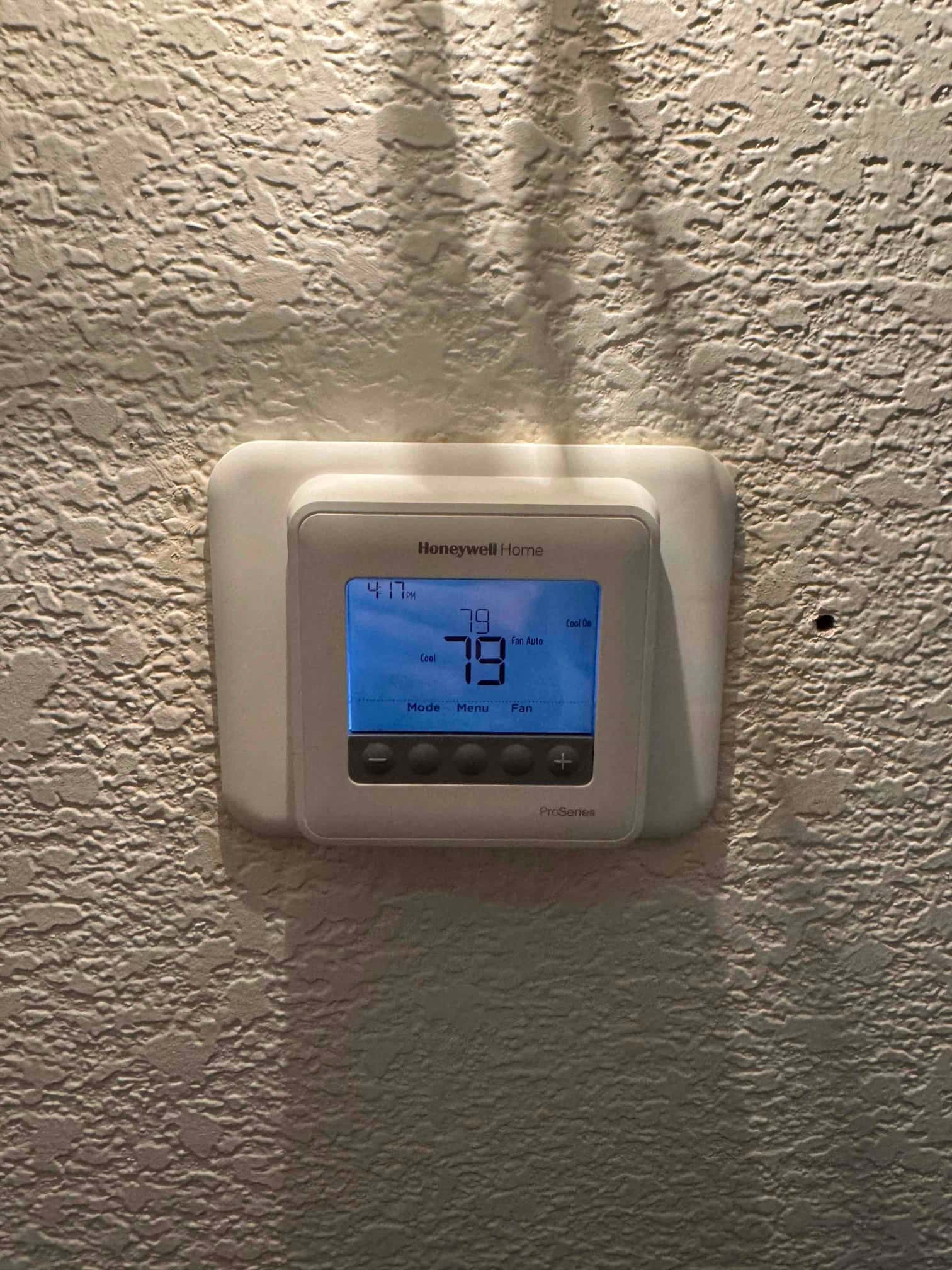 Wall-mounted digital thermostat displays 79° with cooling mode selected and fan set to auto.
