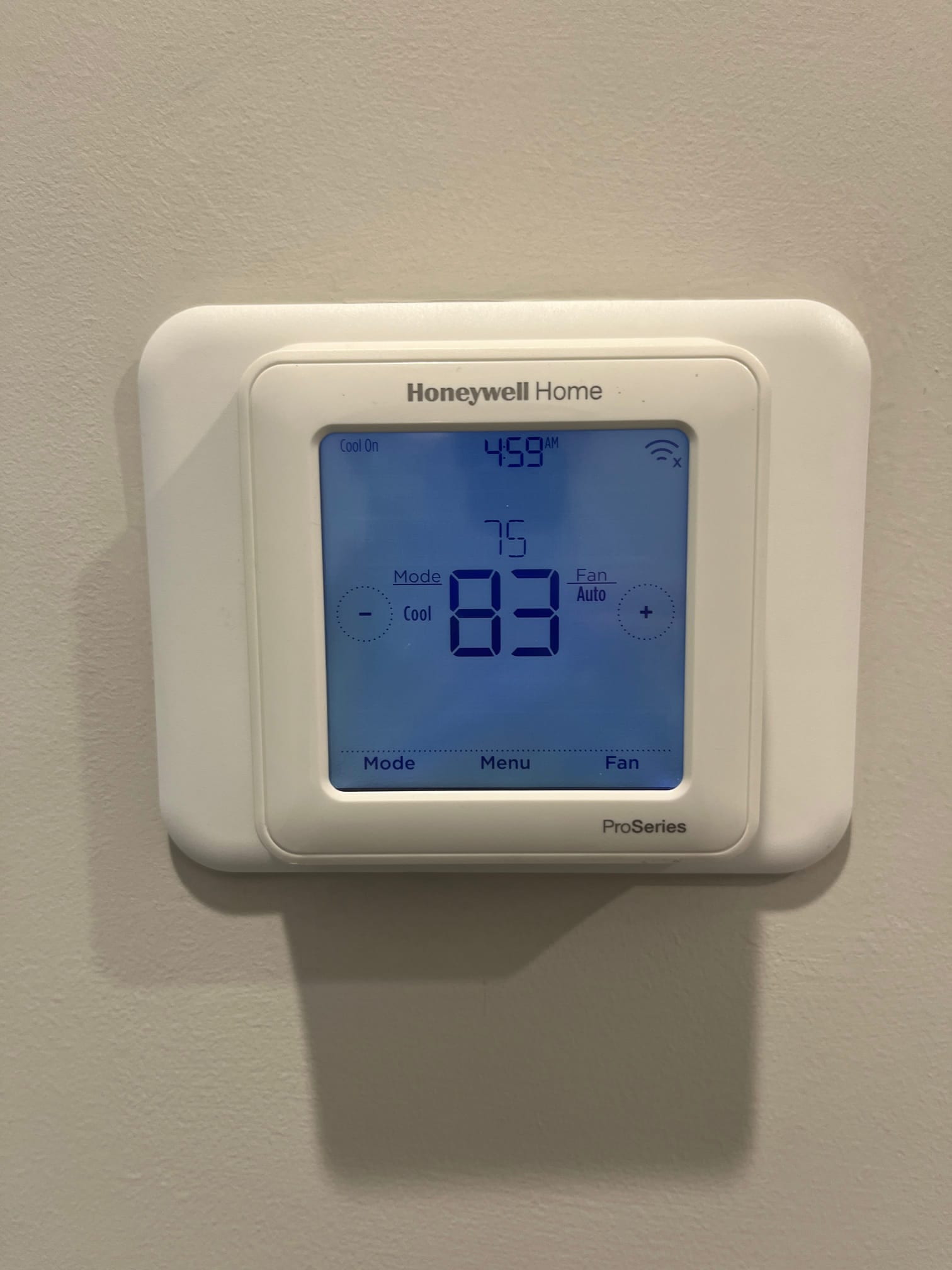 Wall-mounted digital thermostat displays cooling mode active, 4:59 AM, setpoint 75, current temperature reading 83, with fan set to Auto.