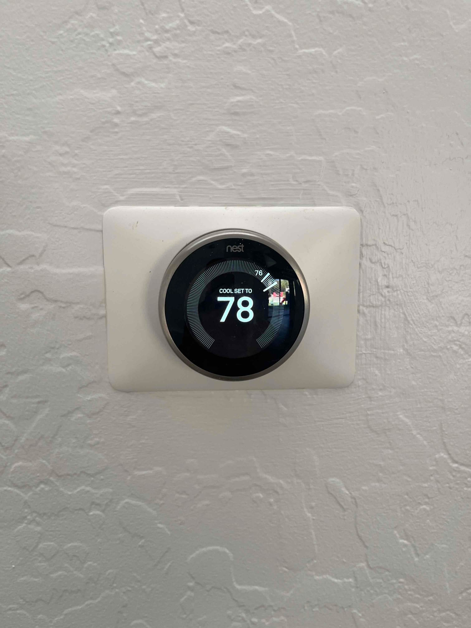 Wall-mounted smart thermostat display shows cooling mode with the temperature set to 78 degrees.