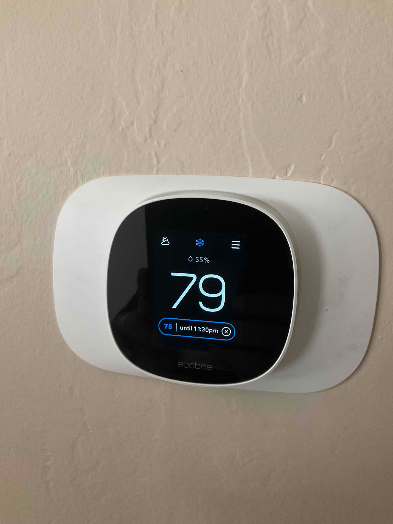 Wall-mounted smart thermostat displays 79 degrees with cooling mode active and 55% humidity on the screen.