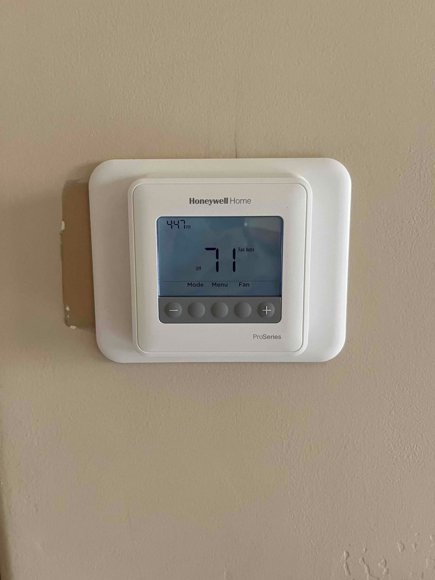 Wall-mounted thermostat with backplate installed; display shows 71, system Off, and fan set to Auto.