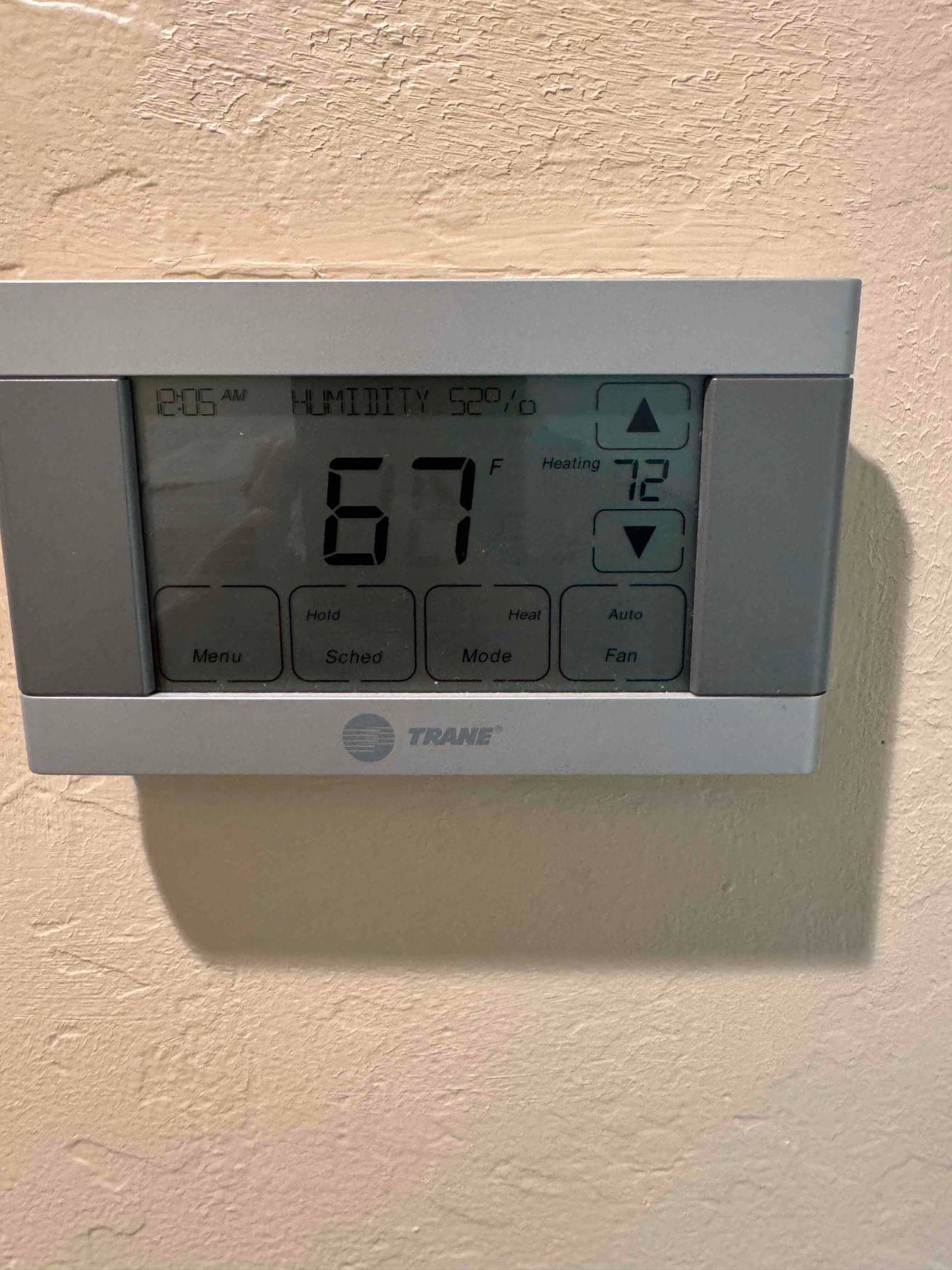 Wall-mounted thermostat display shows 67°F room temperature, 52% humidity, and heating setpoint at 72°F.