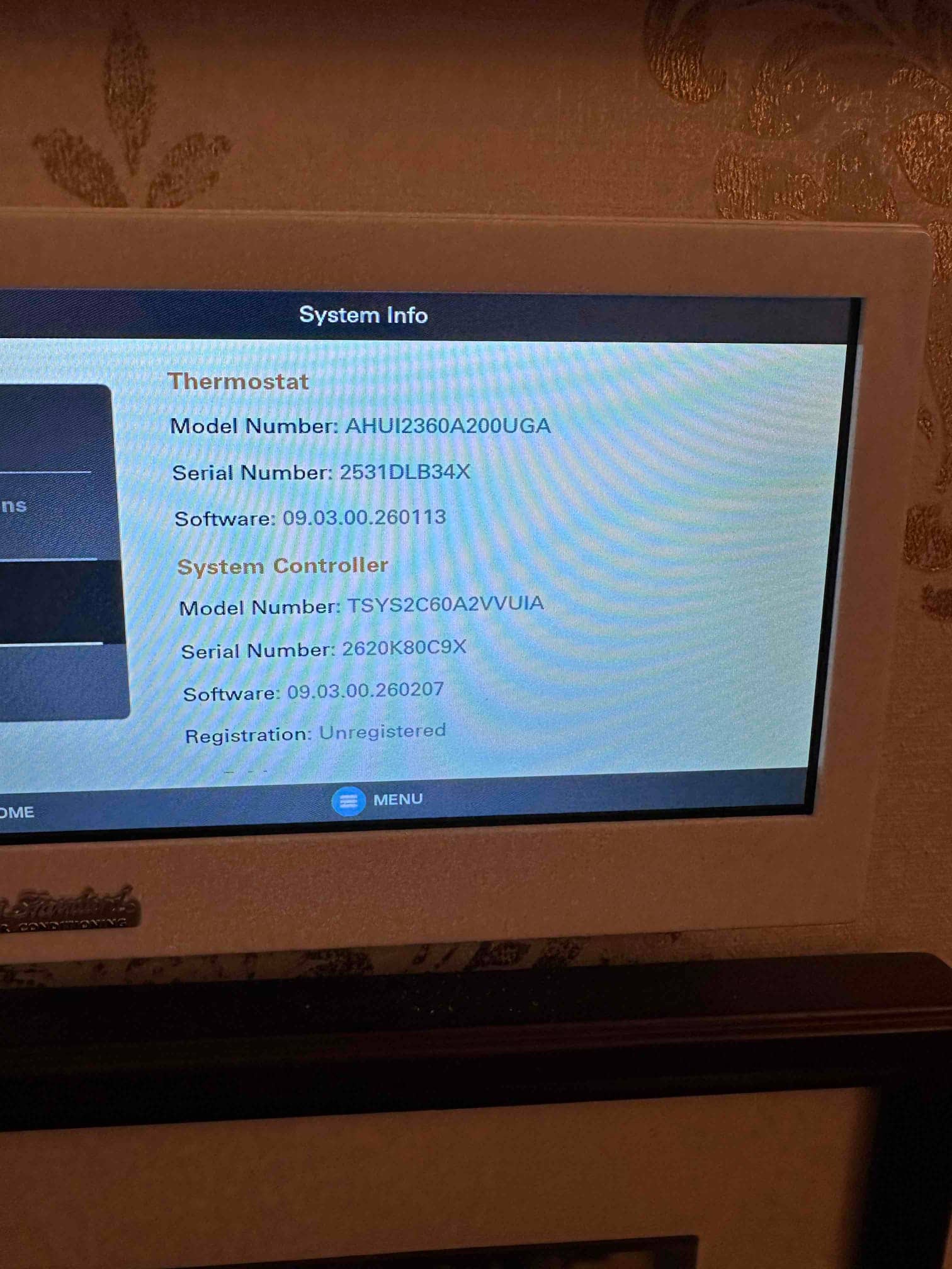 Wall-mounted touchscreen thermostat displays system information for thermostat and system controller during setup.