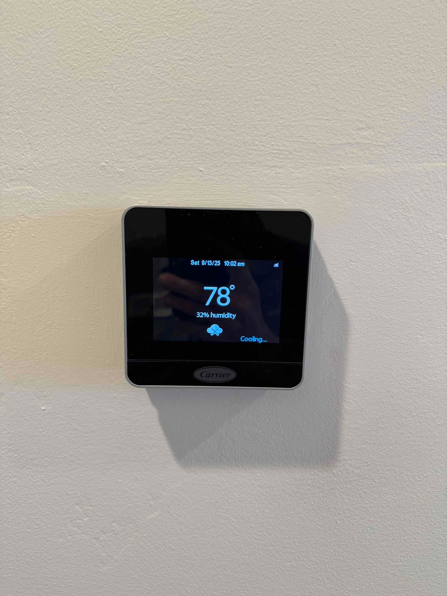 Wall-mounted touchscreen thermostat shows 78° indoor temperature and 32% humidity with the system status indicating cooling.