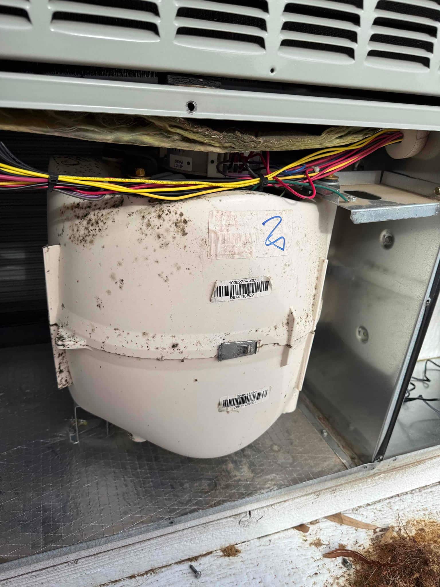 White plastic blower housing inside the unit with bundled control wiring and dirt on the surface.