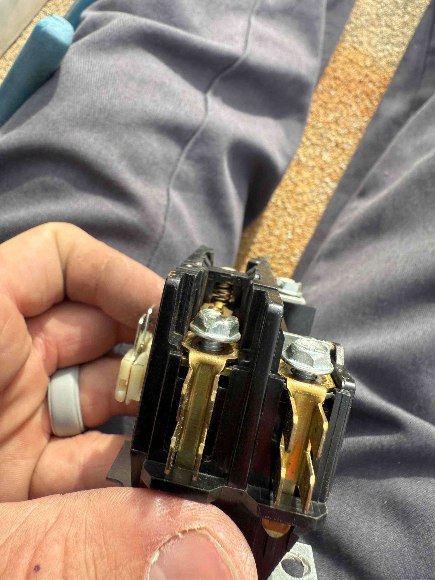 Two-pole contactor held in hand, showing contact surfaces, mounting screws, and the center spring assembly.