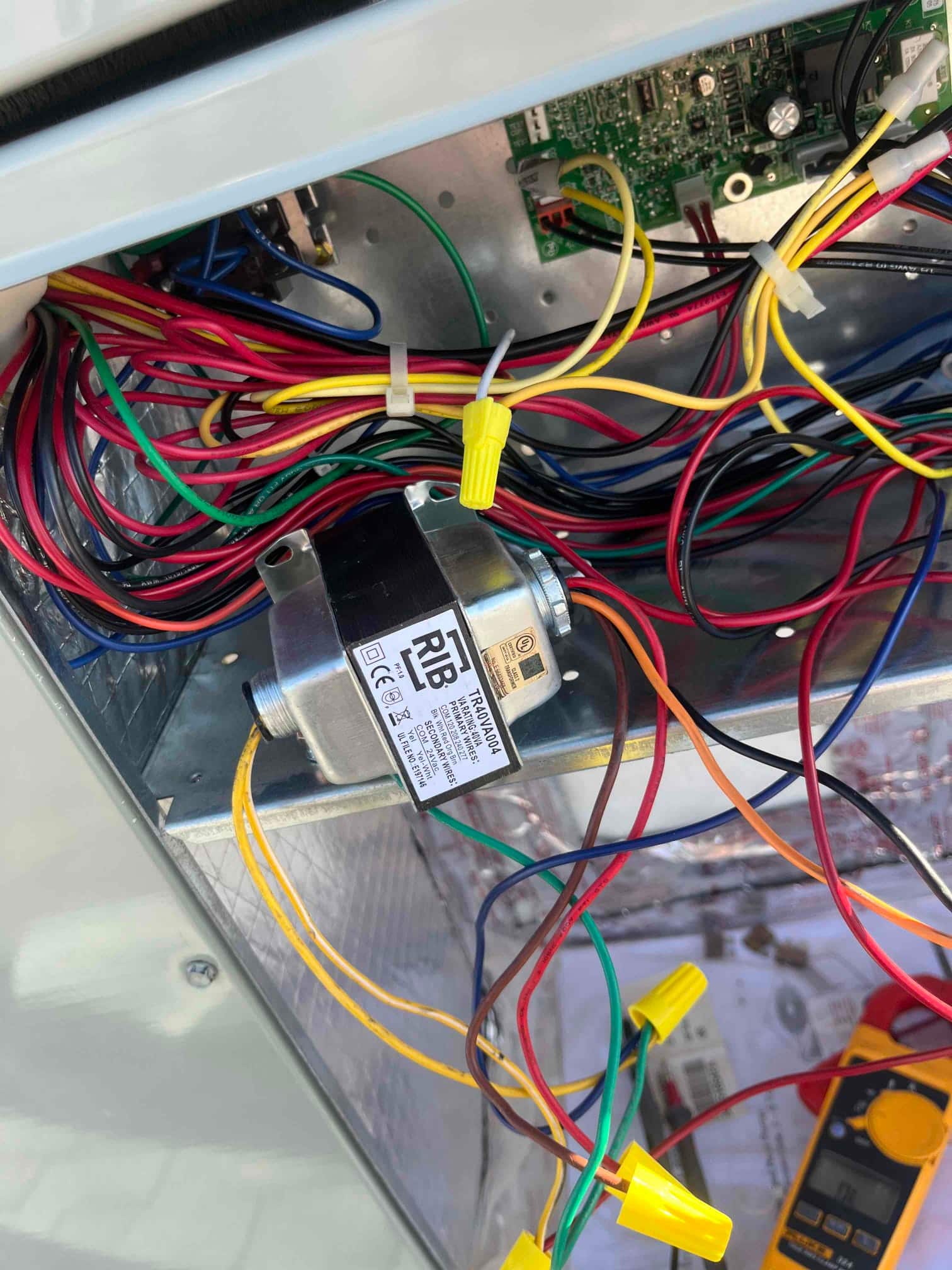 Control compartment open, showing relay module, circuit board, and bundled low-voltage wiring with wire connectors and splices.