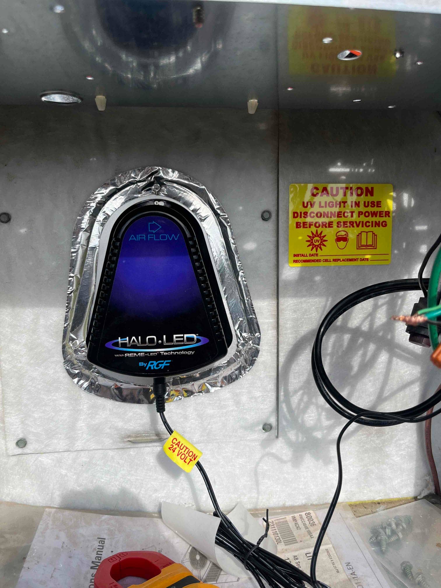 In-duct UV light assembly mounted inside the air handler plenum with caution label and 24-volt wiring visible.