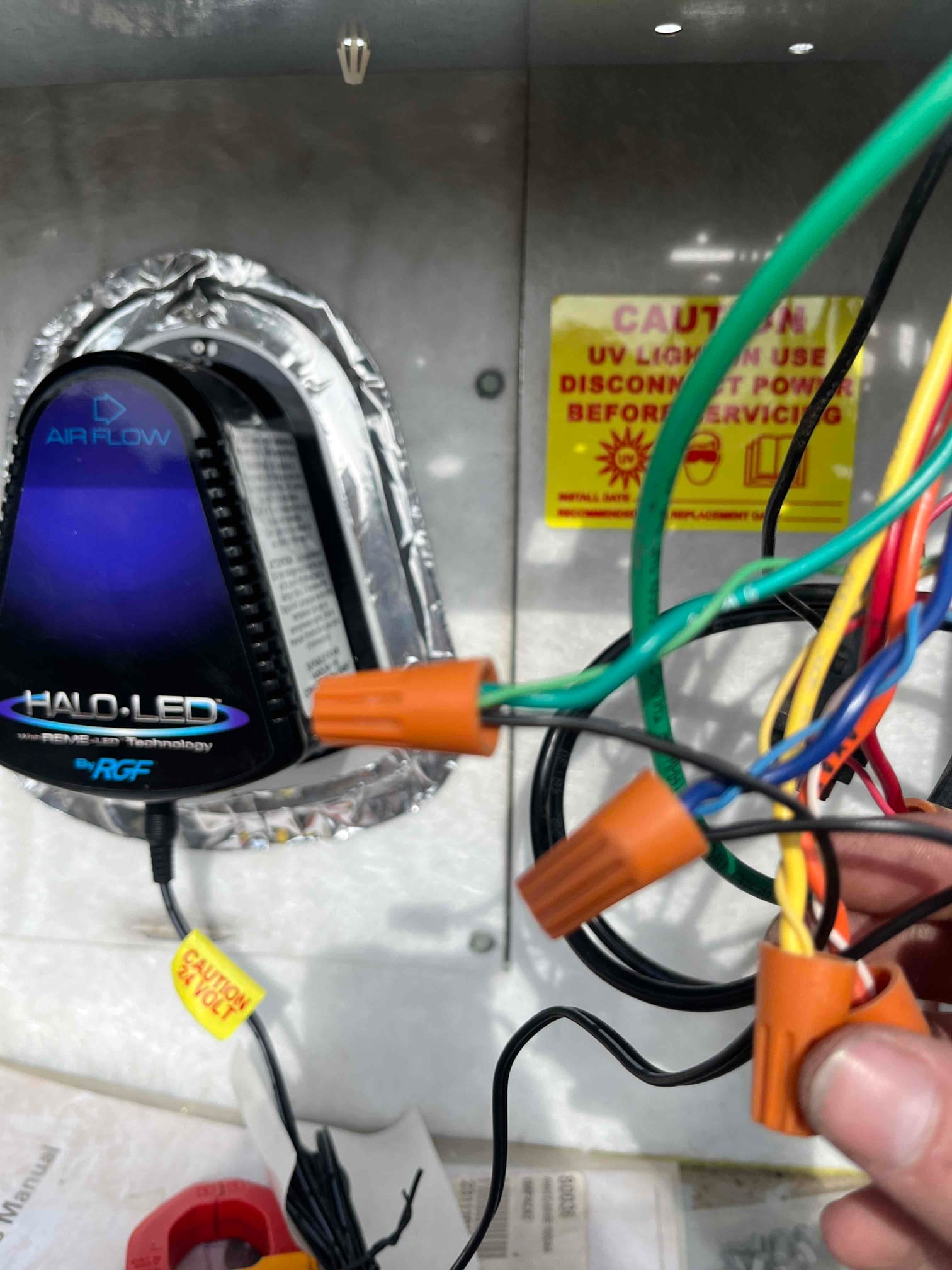 UV air treatment device mounted inside the air handler cabinet, with multiple colored wires secured by orange wire nuts.