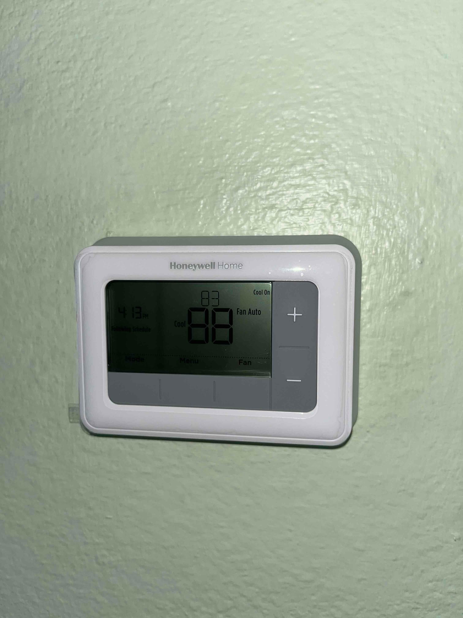 Wall-mounted digital thermostat displays 83 with cooling on and fan set to Auto.