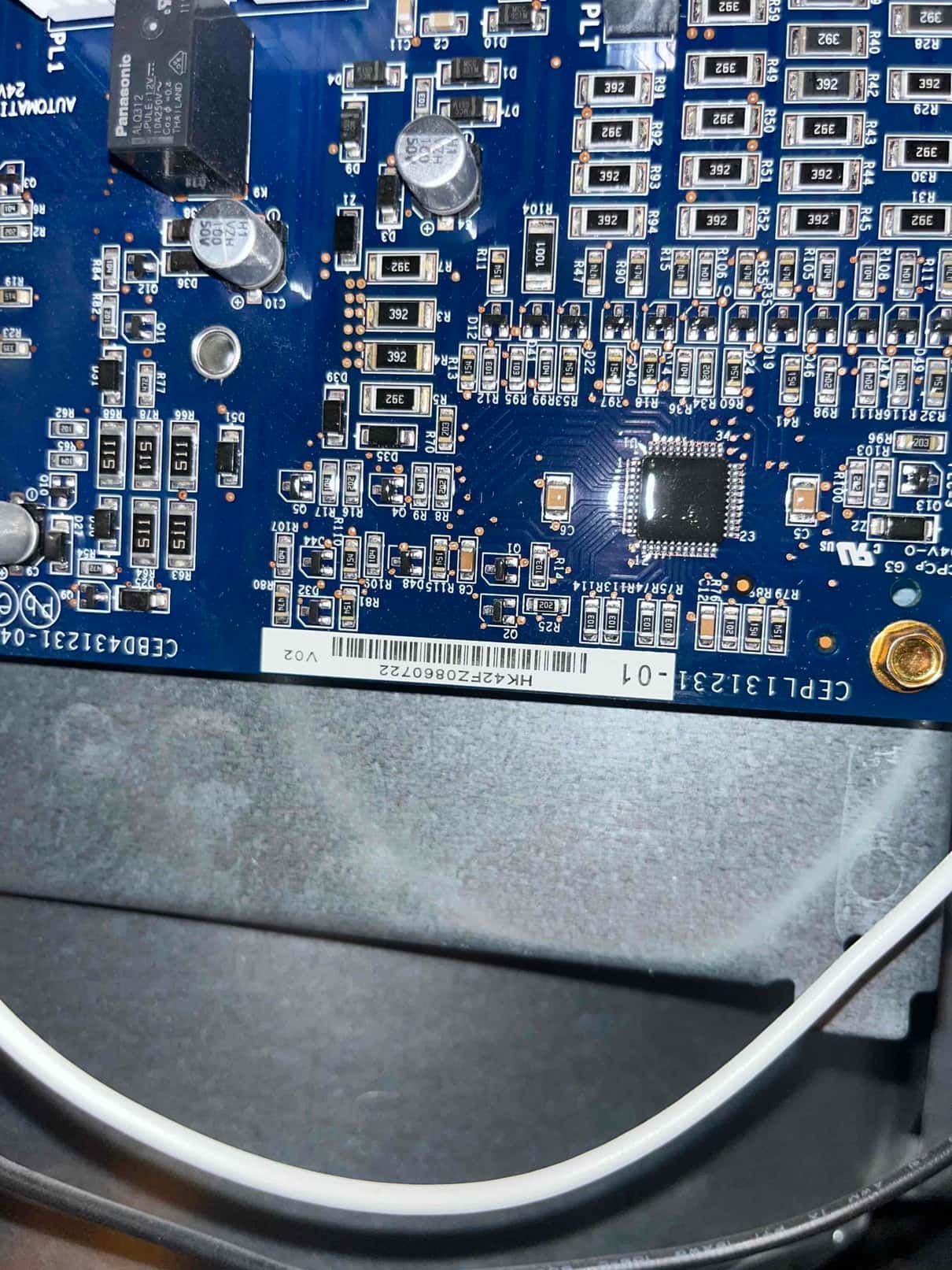 Control circuit board inside the unit, showing surface-mounted components, two electrolytic capacitors, an integrated chip, and a printed barcode label.