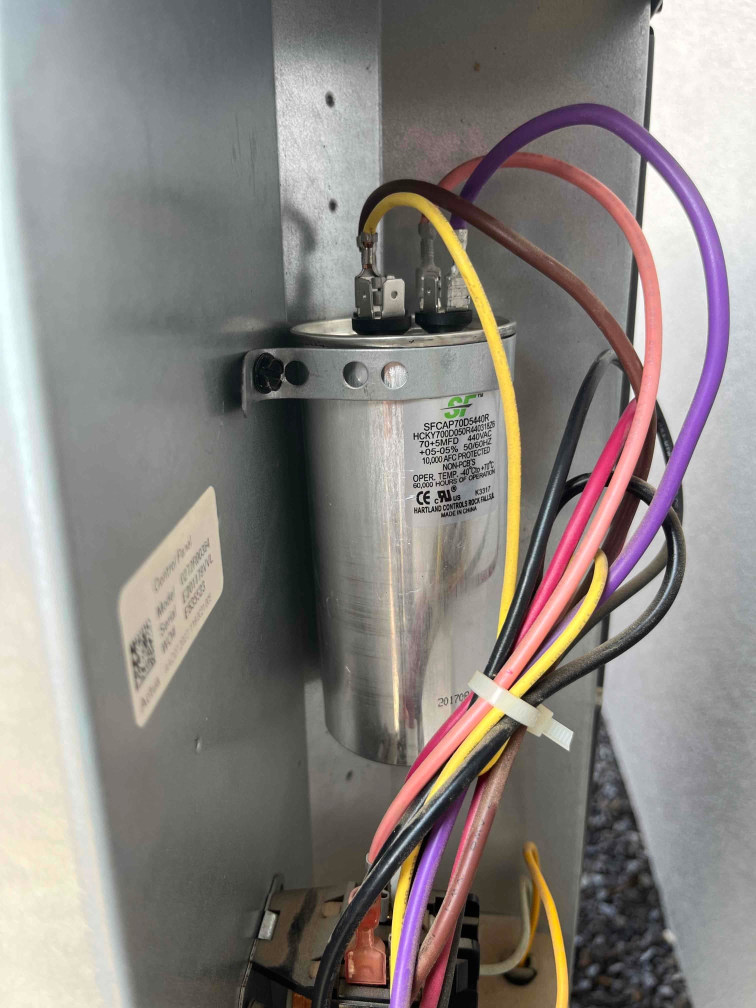 Dual-run capacitor installed in the condenser control compartment, with multiple colored wires connected to its labeled terminals.