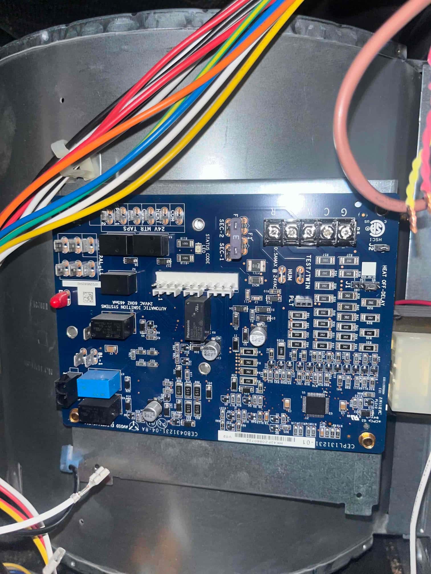 Furnace control board mounted in the blower compartment with multiple connected wires and labeled terminals and fuses.