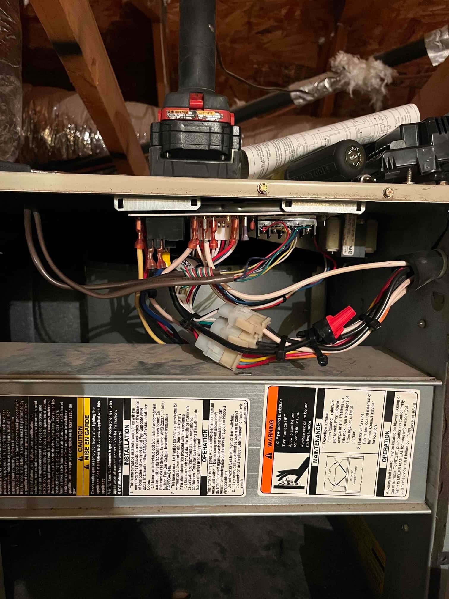 Open air handler control compartment shows multiple wiring harnesses, spade terminals, wire connectors, and a control board above instruction and safety labels on the blower panel.