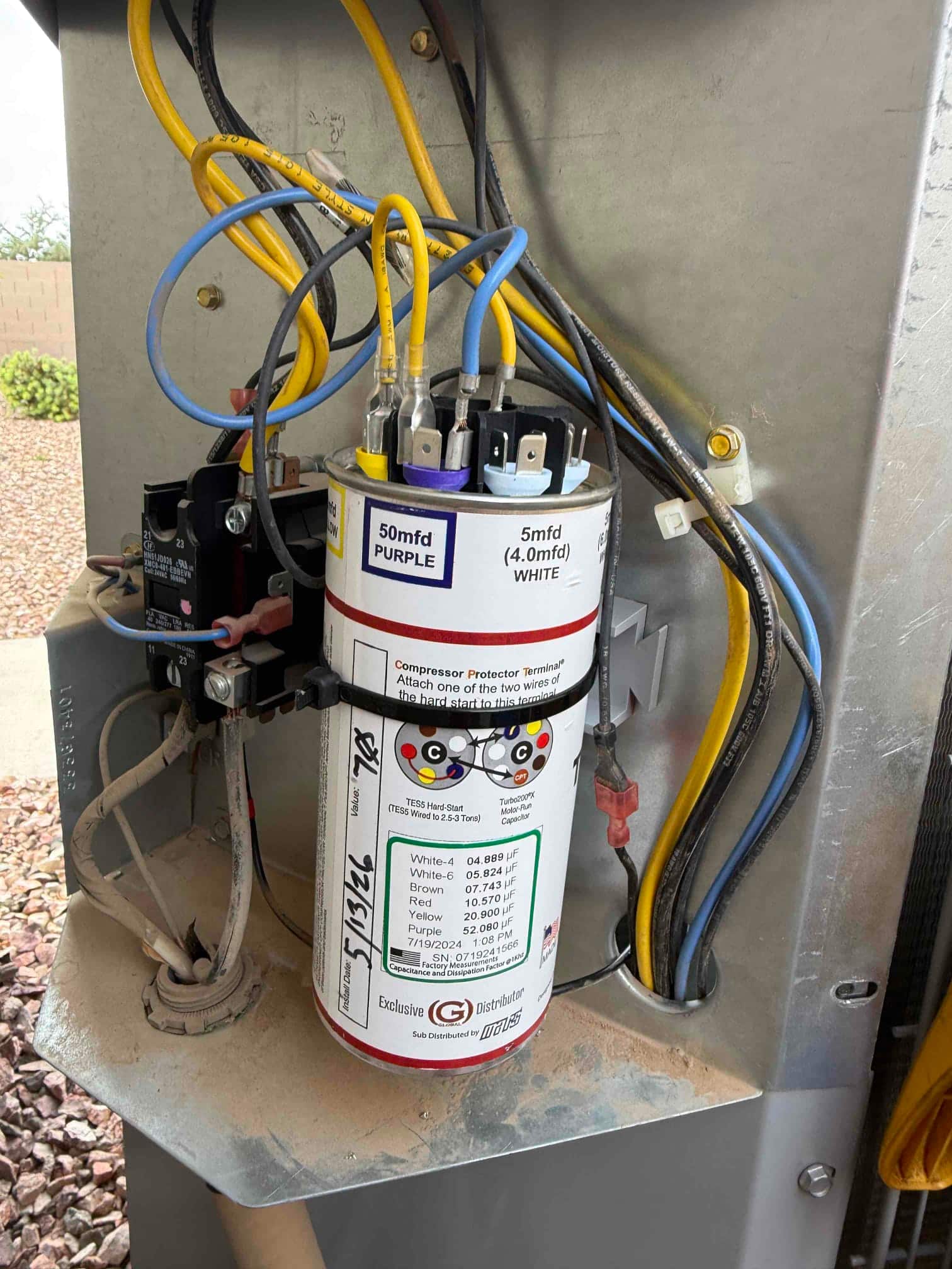 Run capacitor mounted in condenser compartment with wiring connected; printed specs visible: 50 mfd PURPLE and 5 mfd WHITE.