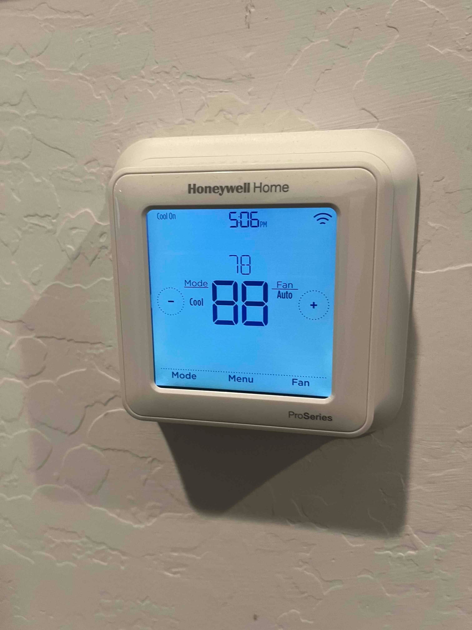 Wall-mounted digital thermostat display shows Cool On, 5:06 PM, room temperature 78, and fan set to Auto.