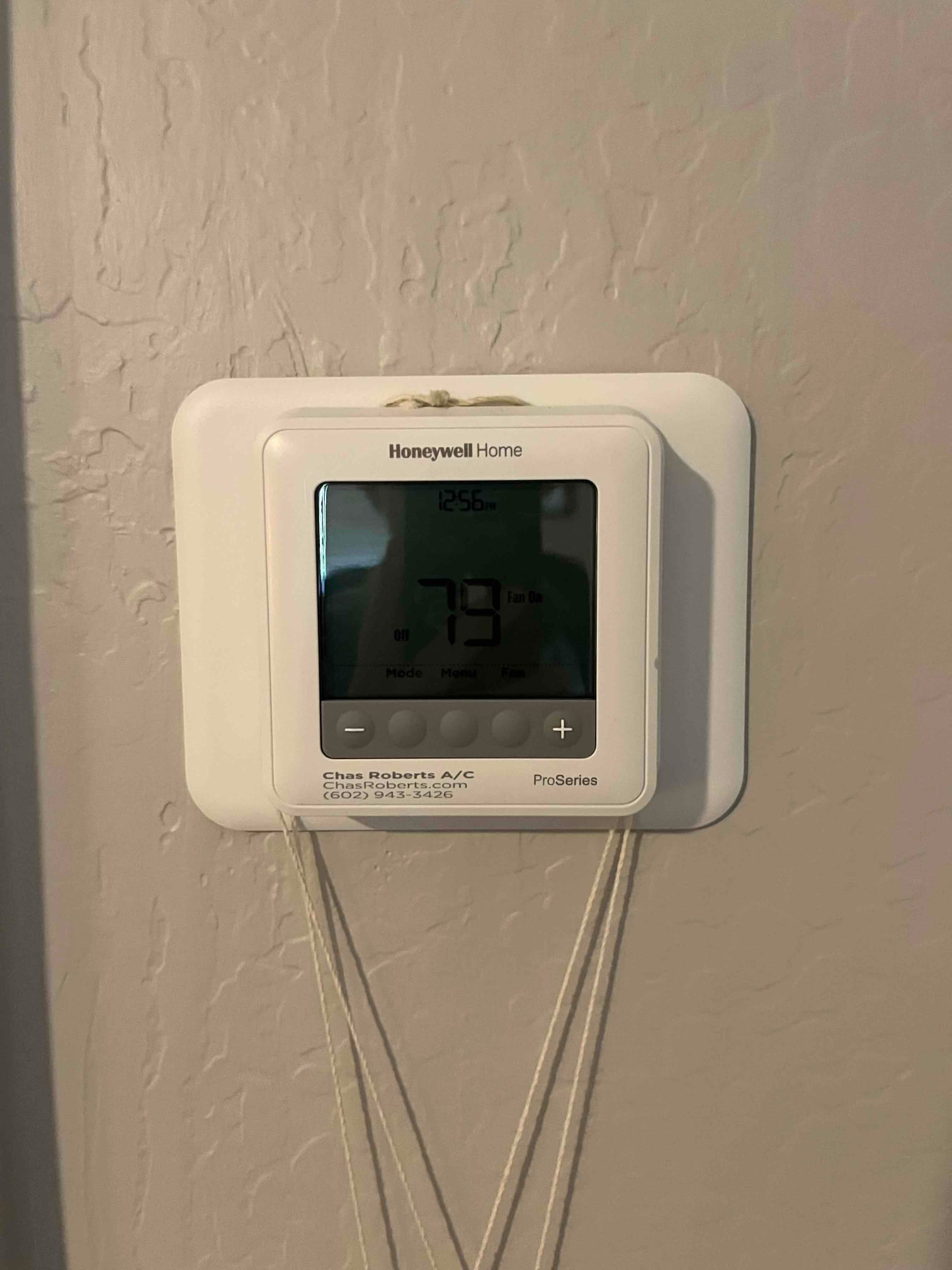 Wall-mounted digital thermostat displays 79 with the Fan On indicator visible and control buttons below.