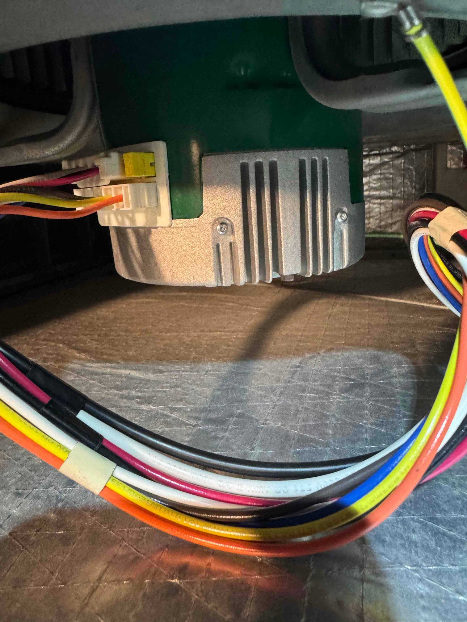 Blower motor inside the air handler with a wiring harness connected and color-coded leads routed along insulation.